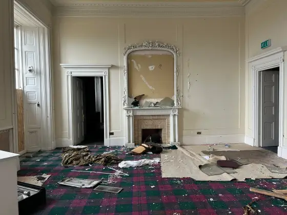 Fireplace room with debris and torn wallpaper at the abandoned Airth Castle and hotel complex.